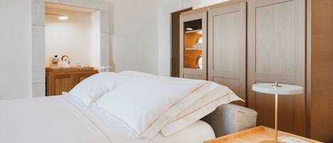 A hotel room with a bed, bedside table, lamp, and a wooden wardrobe.