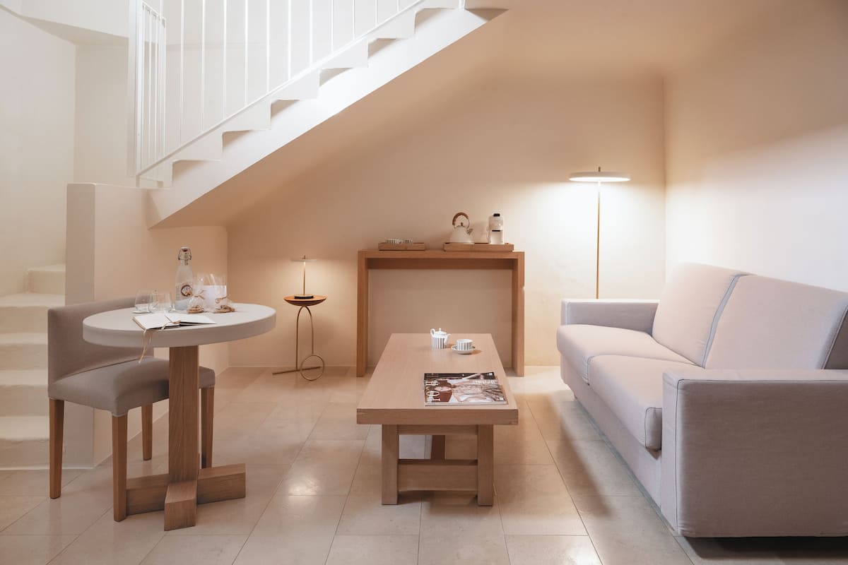 Ein modernes Wohnzimmer mit Treppe, einem runden Tisch mit Stühlen, einem Sofa und einem Couchtisch.
