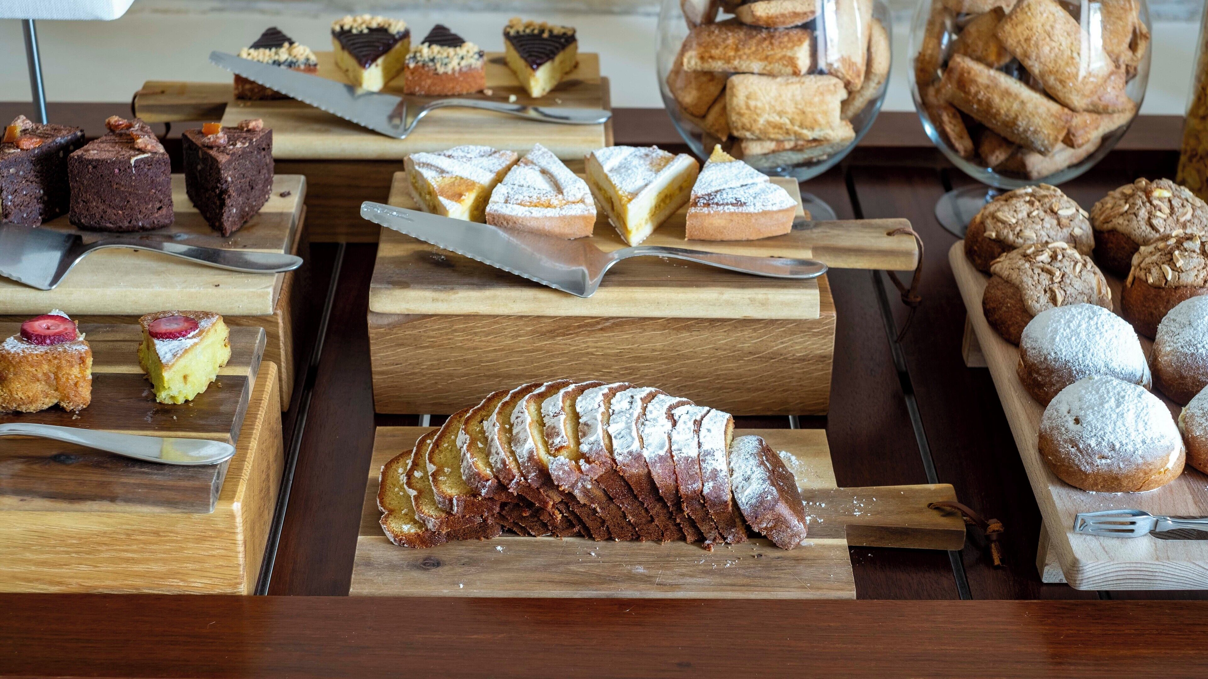 Una variedad de pasteles y postres expuestos sobre tablas de madera.