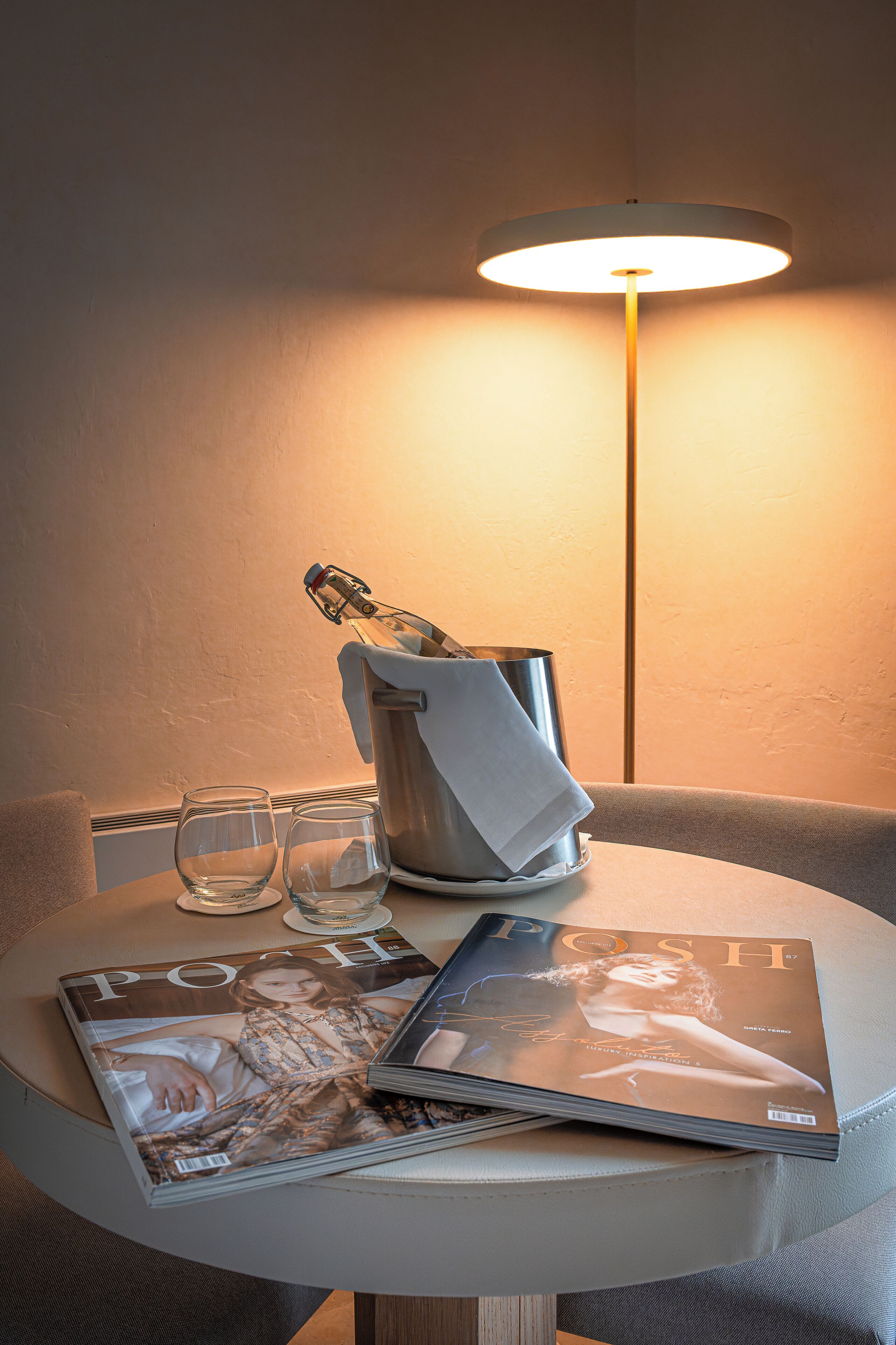 A table with a magazine, a bottle, and glasses.
