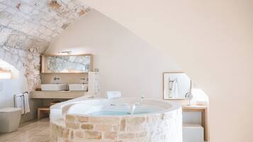 Une salle de bain avec une baignoire en pierre, un lavabo et un miroir.