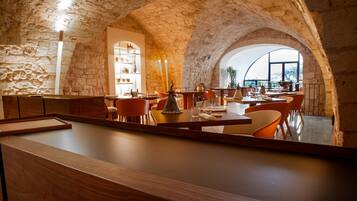 Un ristorante con pareti in pietra, soffitti a volta e un'isola centrale con posti a sedere.