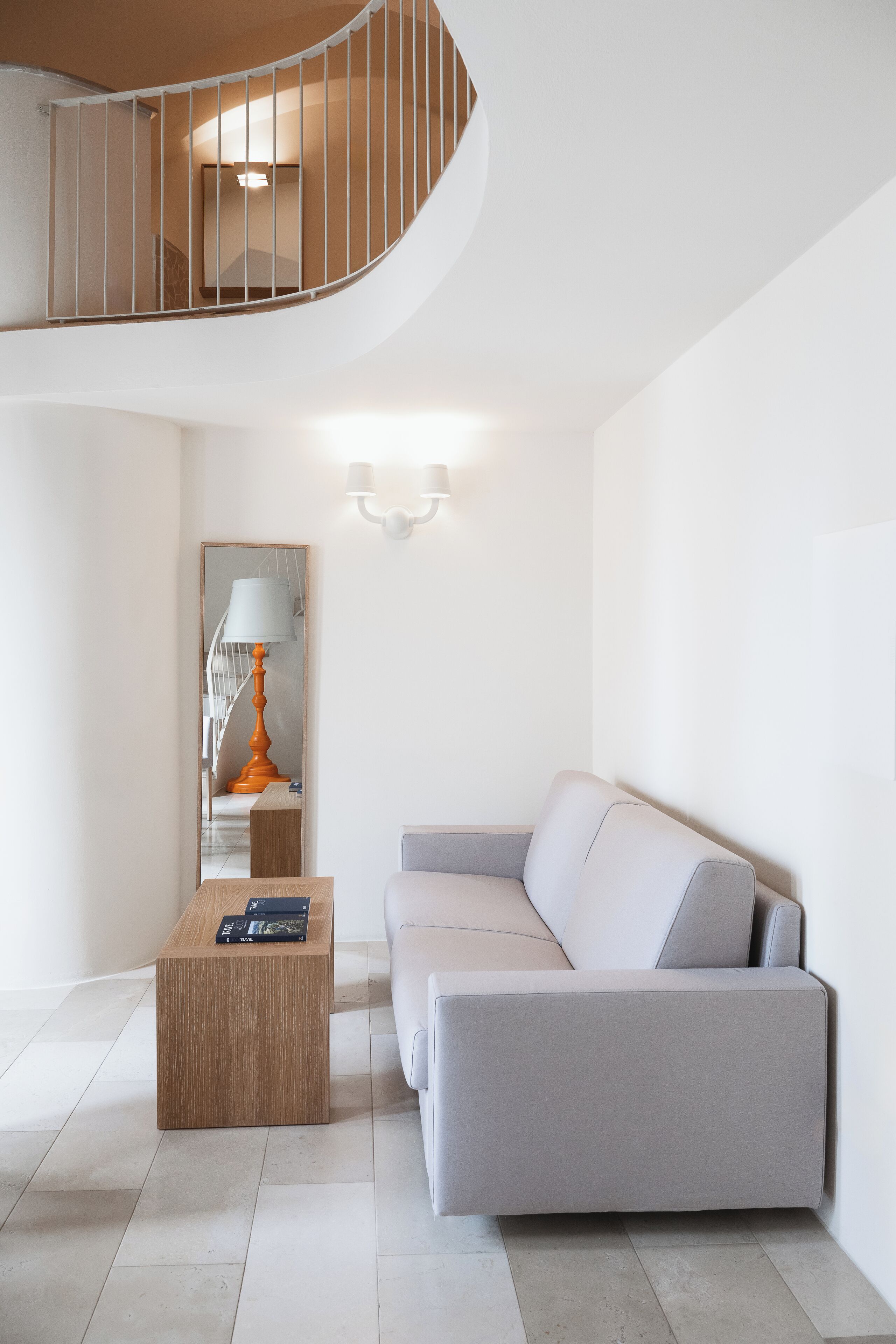 Una sala de estar moderna con una escalera curva, un sofá, una mesa de centro y una lámpara.