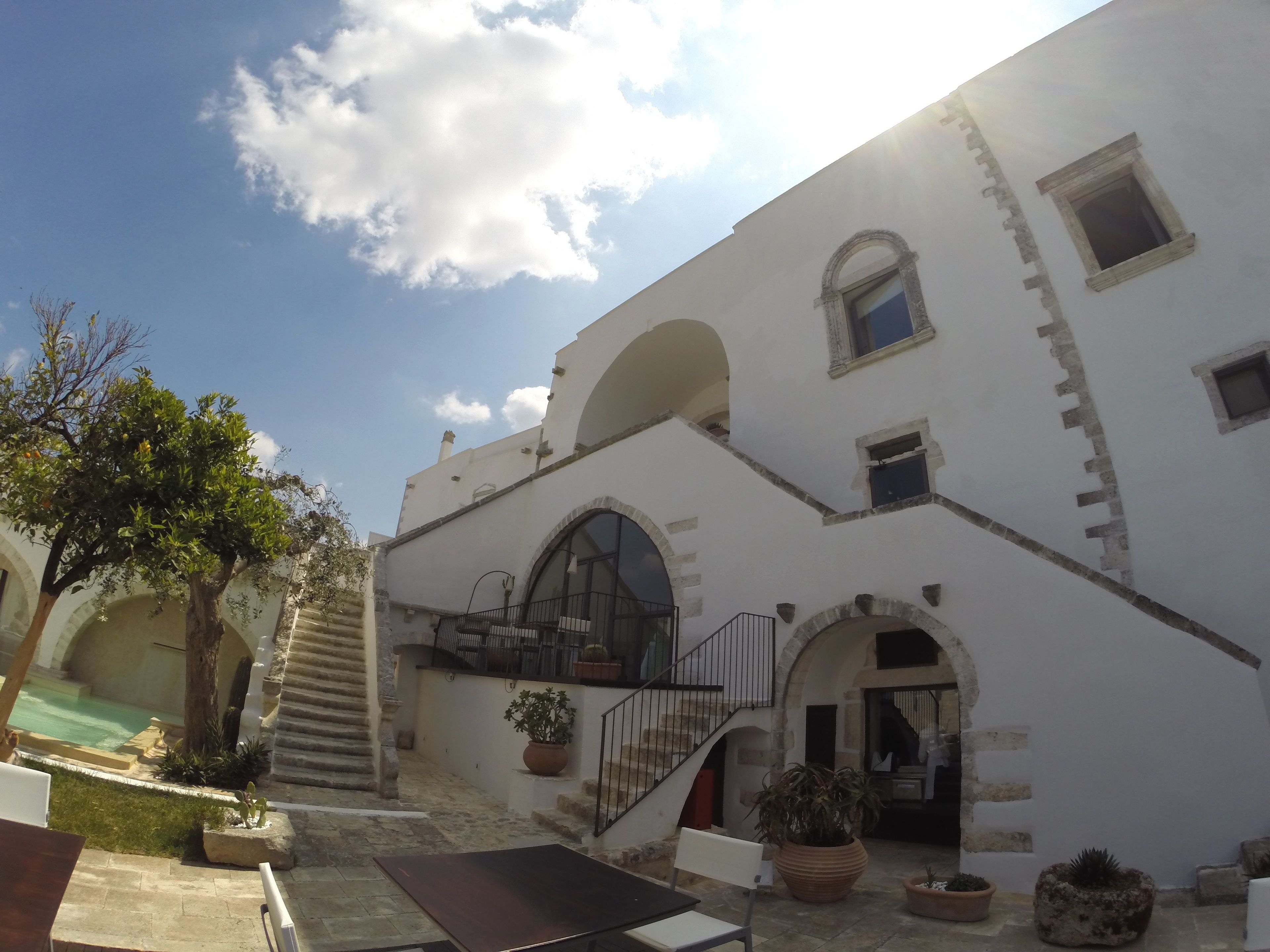 A courtyard with a pool, outdoor seating, and a staircase leading to an upper level.