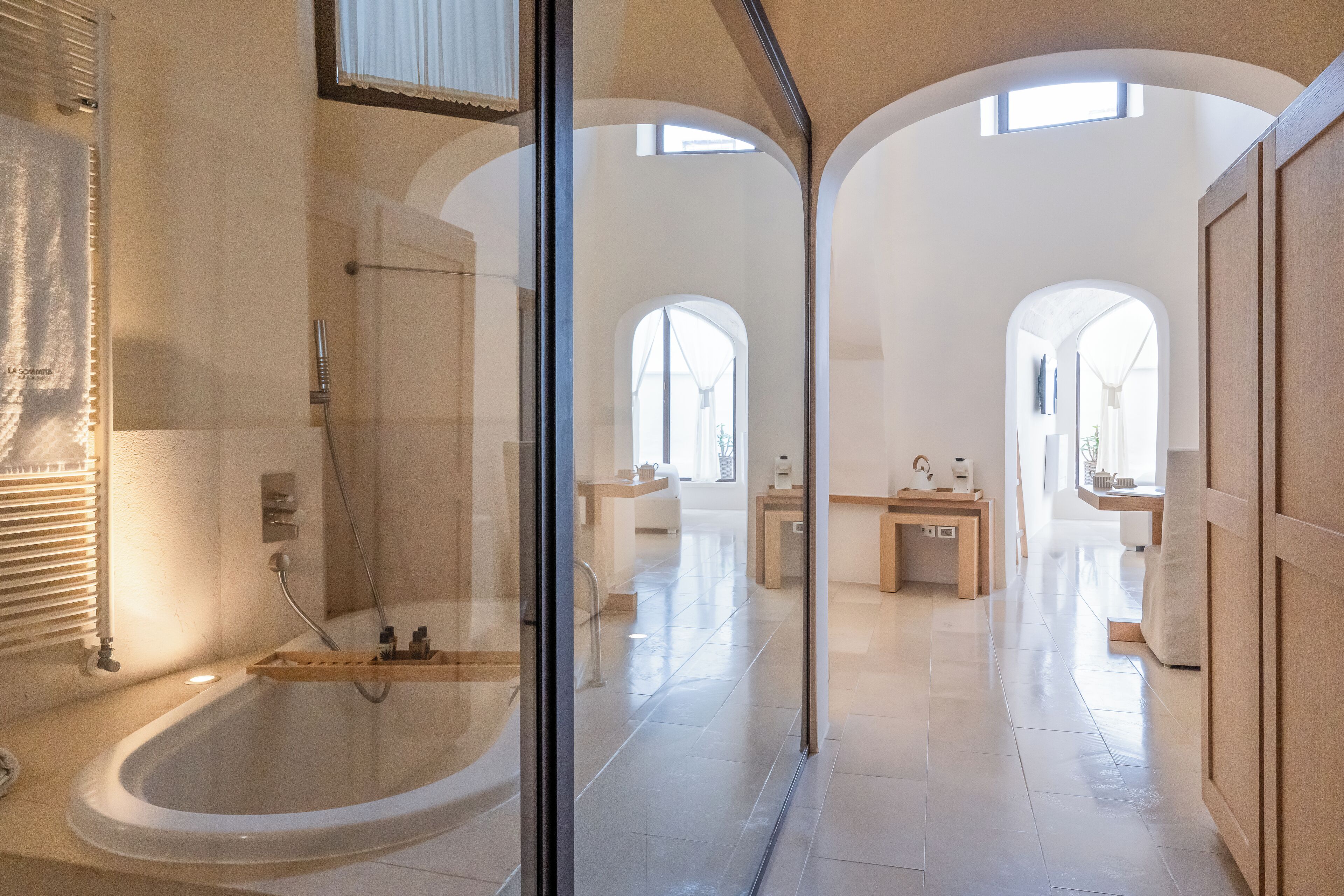 Un baño moderno con ducha envuelta en vidrio, una bañera grande y un tocador con espejo.