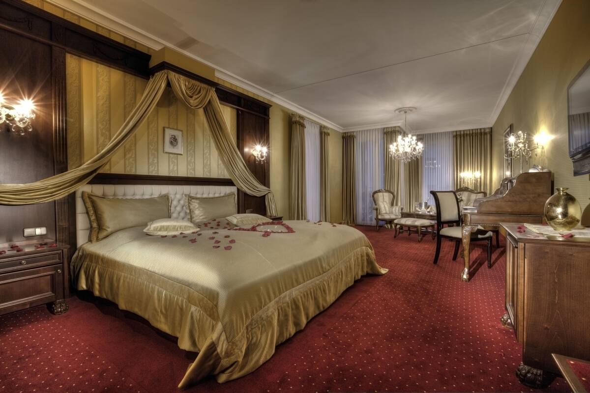 Ein luxuriöses Schlafzimmer mit einem großen Bett, aufwendigen Vorhängen, einer Chandelier und einem Klavier.