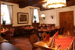 A dining area with wooden tables and chairs, red tablecloths, and decorative napkins. - Hotel zum Erdinger Weissbräu (Erding)