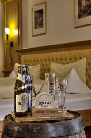 A wooden barrel table with bottles of Erdinger beer, a glass, and a coaster. - Hotel zum Erdinger Weissbräu (Erding)
