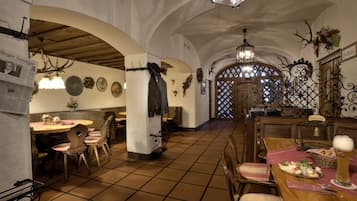 Une auberge traditionnelle avec des tables et des chaises en bois, un sol carrelé et un lustre.