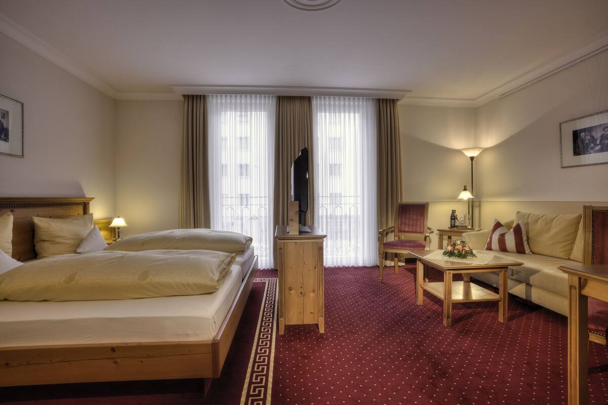 Ein Hotelzimmer mit Bett, Sofa, Couchtisch, Fernseher und Lampe.