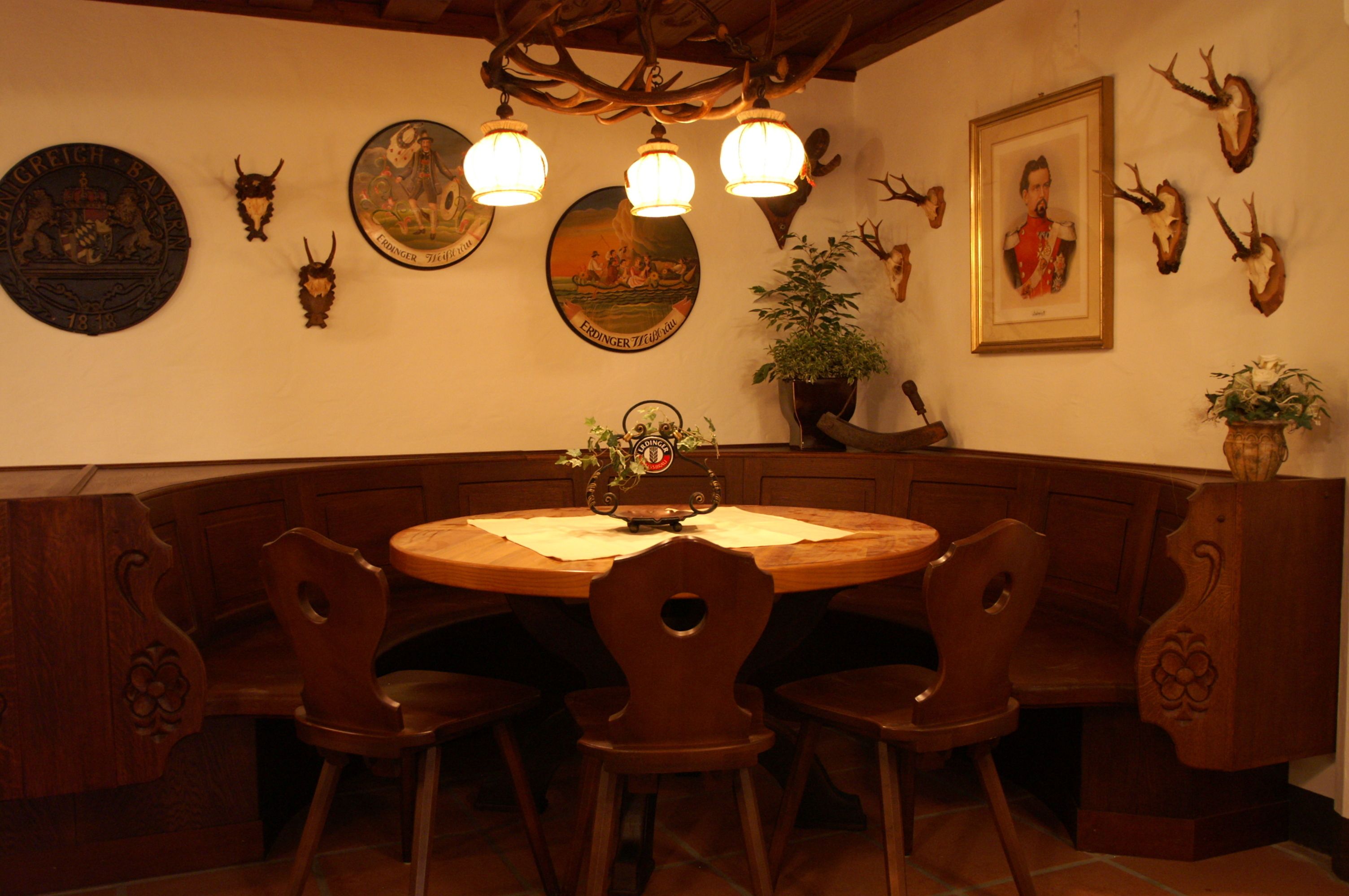 A wooden dining area with a round table, four chairs, and a chandelier.