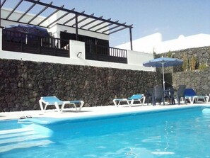Una piscina al aire libre, sombrillas, sillones reclinables de piscina