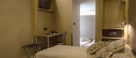 A compact hotel room with a bed, a desk, and a television.