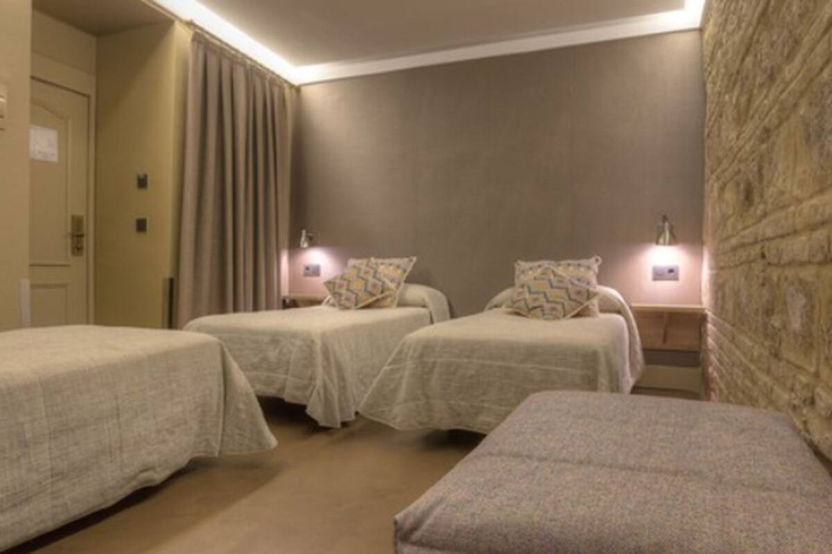 Ein Hotelzimmer mit zwei Einzelbetten, einer kleinen Sitzecke und einer Wand mit Steinverkleidung.