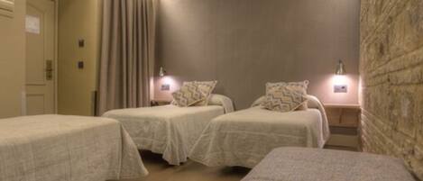 A hotel room with two single beds, a small seating area, and a stone accent wall.