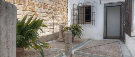 Un patio con paredes de piedra, plantas en macetas y suelo de baldosas.