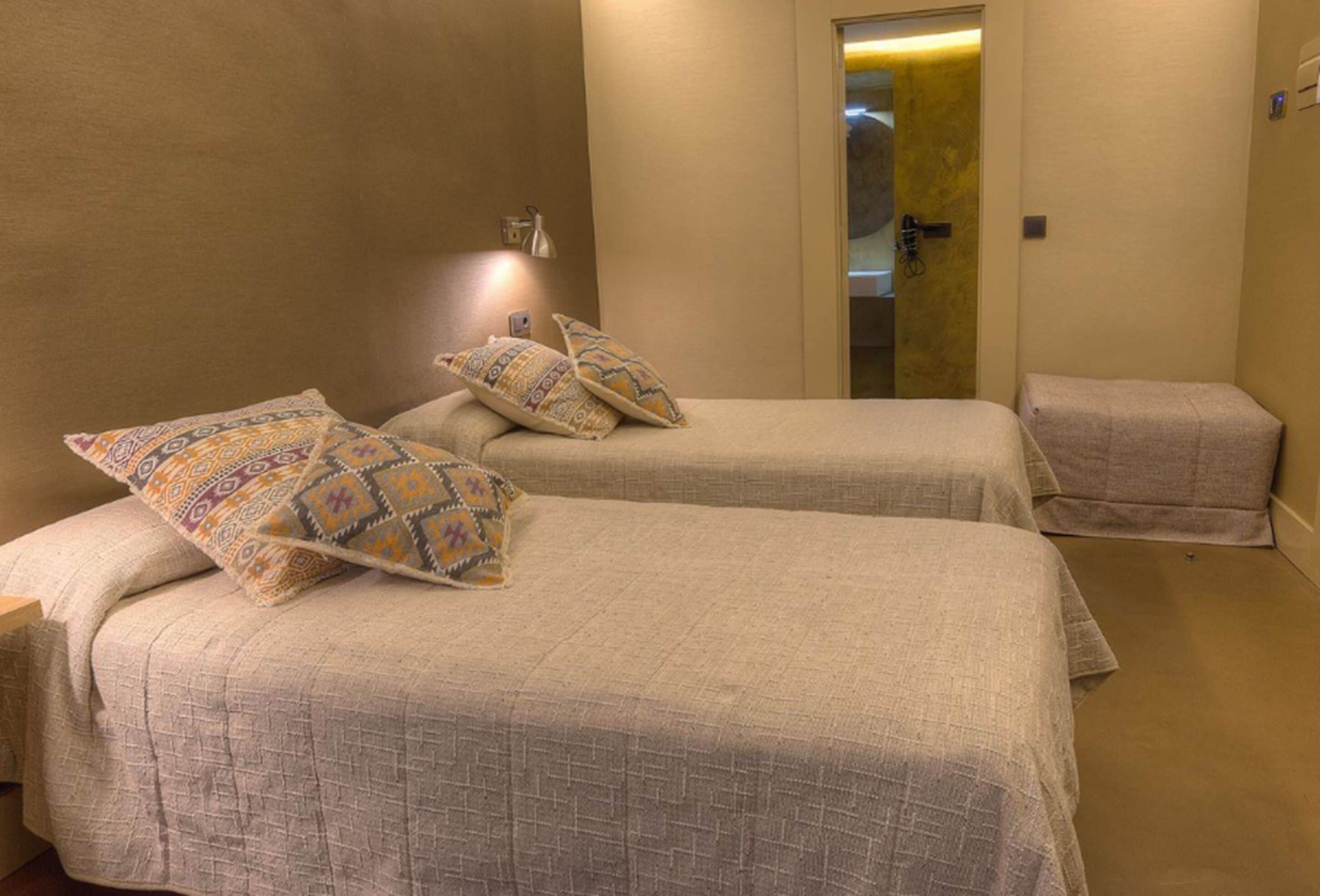Une chambre d’hôtel avec deux lits, chacun agrémenté d’oreillers à motifs, d’une lampe de chevet et d’une petite table de chevet.