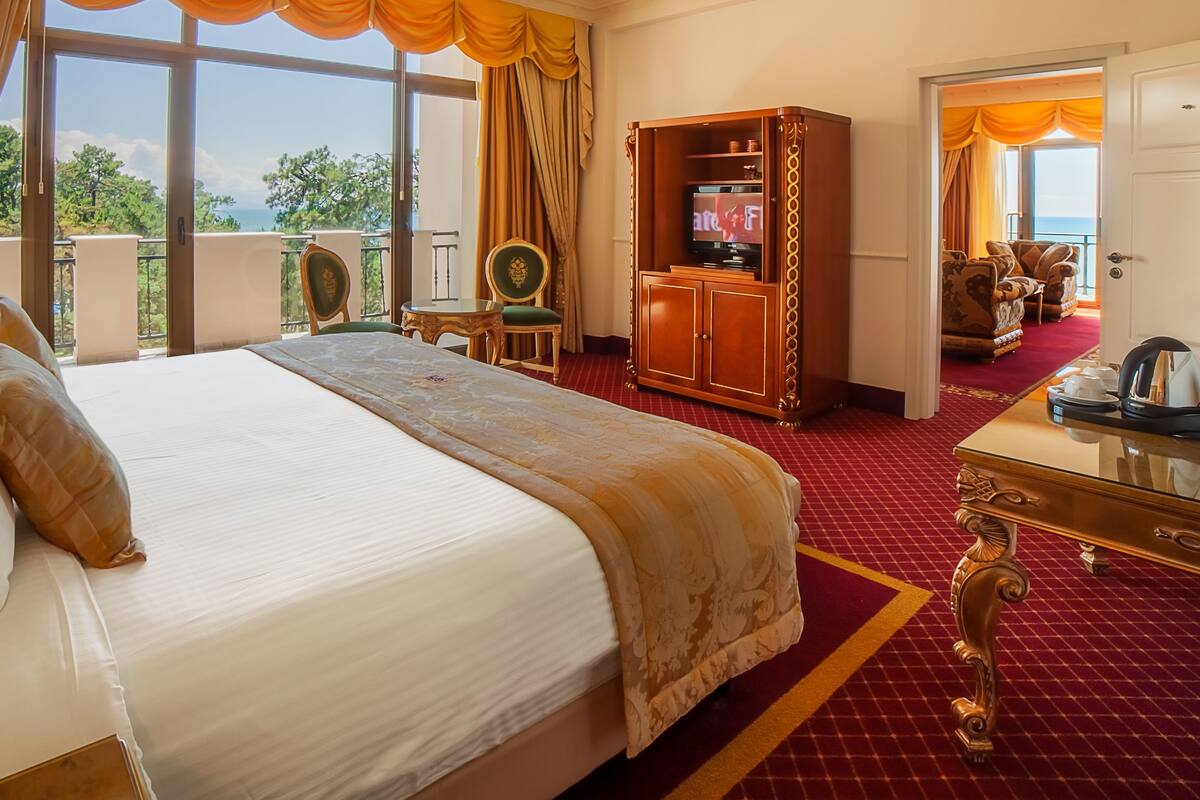 A hotel room with a large bed, a desk, a television, and a view of the outdoors.