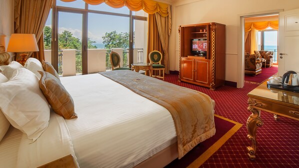 A hotel room with a large bed, a desk, a television, and a view of the outdoors. - Georgia Palace Hotel & SPA (Kobuleti)