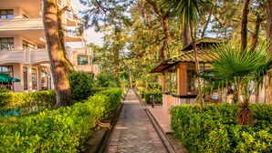 Un chemin bordé d’une végétation luxuriante et un bâtiment doté de balcons et d’une zone abritée.