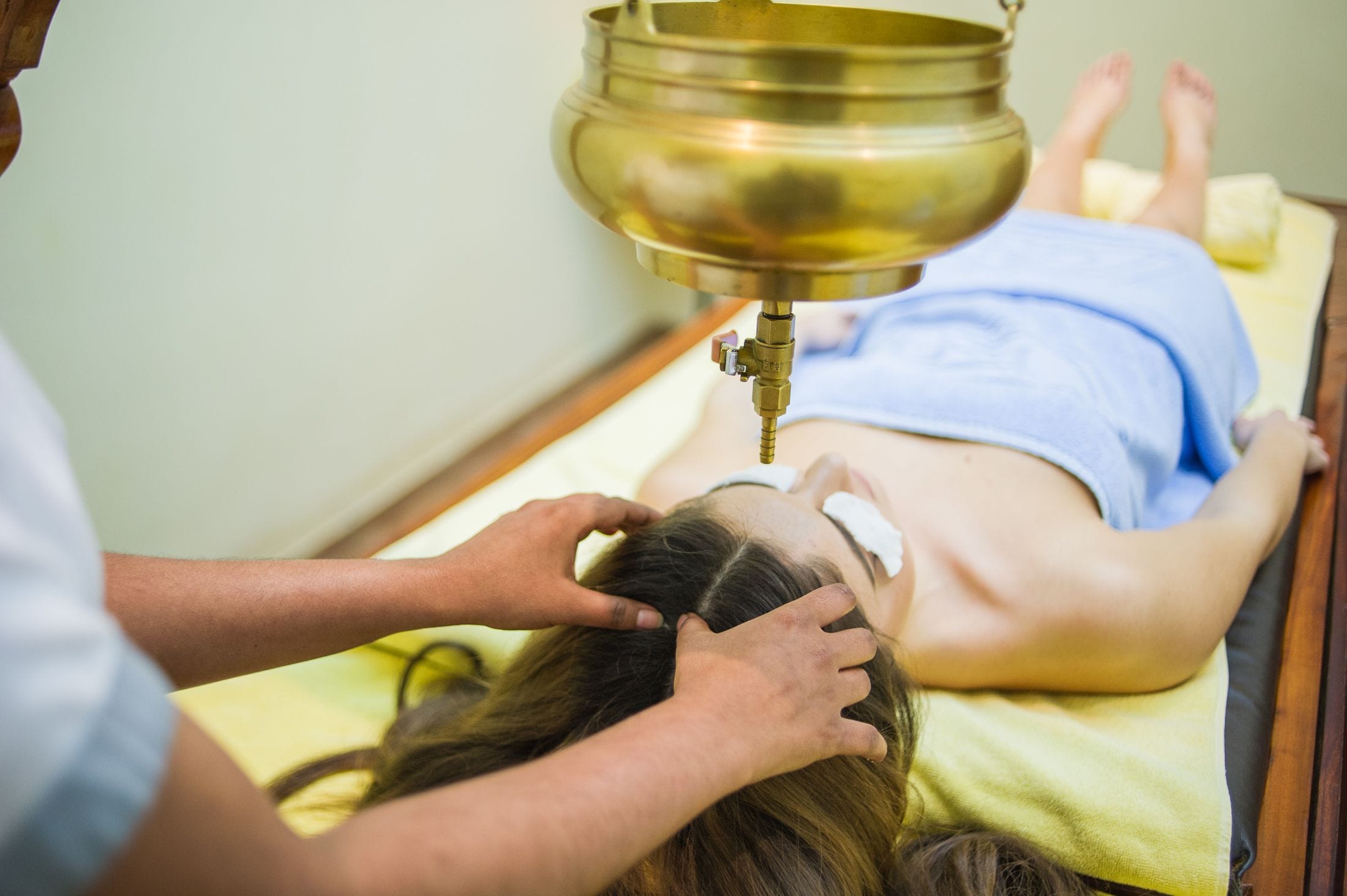 Eine Person bekommt eine Kopfmassage mit einem Metall-Kopfmassager.