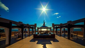 Une terrasse ensoleillée avec un espace salon central et une vue sur la mer.