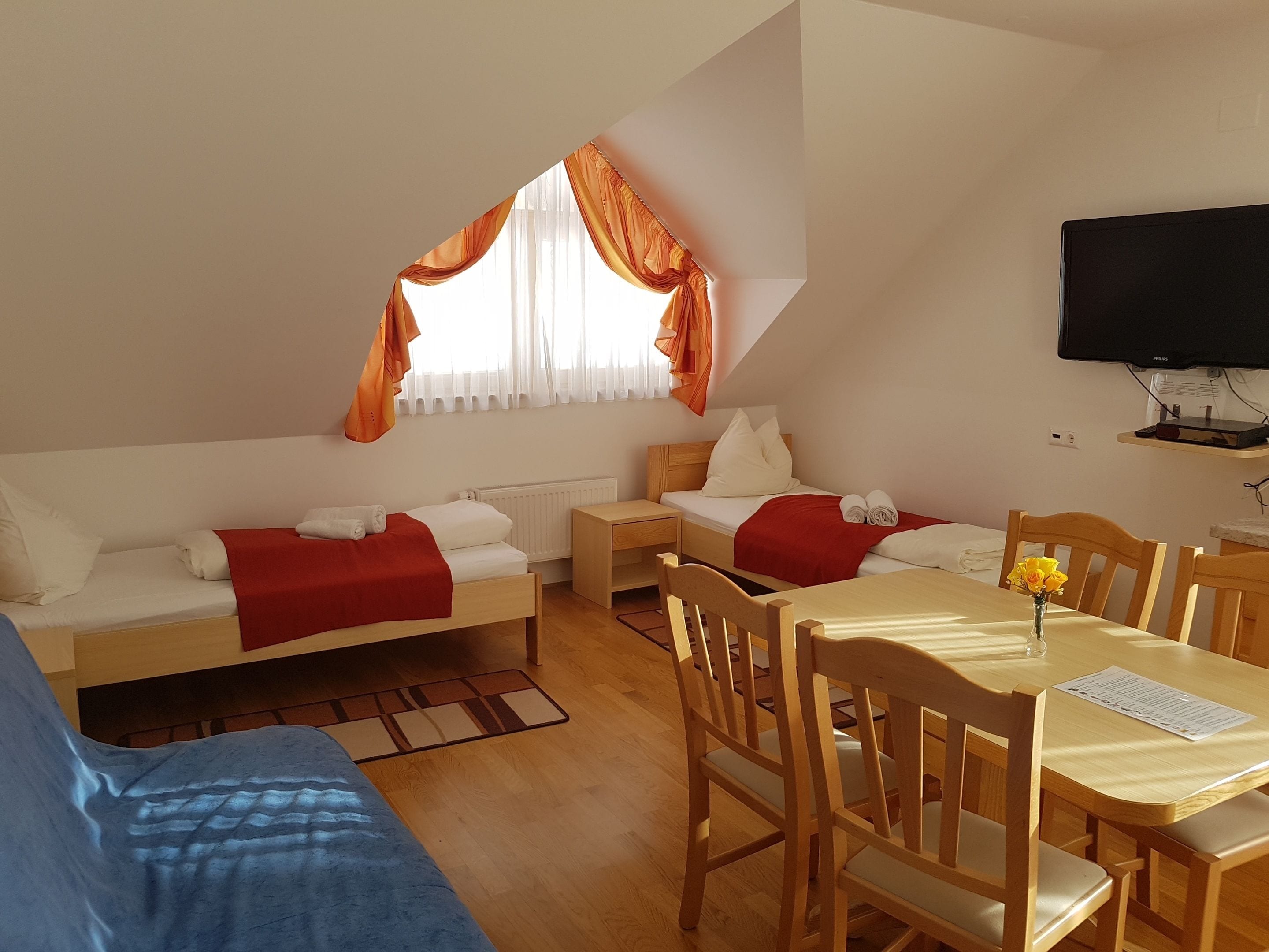 Una habitación pequeña y acogedora con dos camas, una mesa de comedor y un televisor.