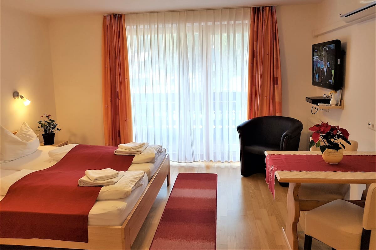 A hotel room with two beds, a desk, a chair, a TV, and a window with curtains.