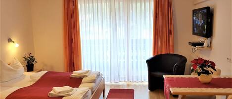 A hotel room with two beds, a desk, a chair, a TV, and a window with curtains.