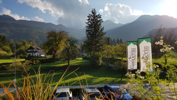 Ländliche Landschaft mit Bergel in der Ferne, ein weißes Gebäude und geparkte Autos.
