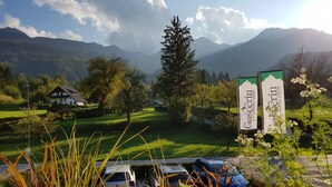 A rural landscape with a mountain backdrop, a white building, and parked cars.