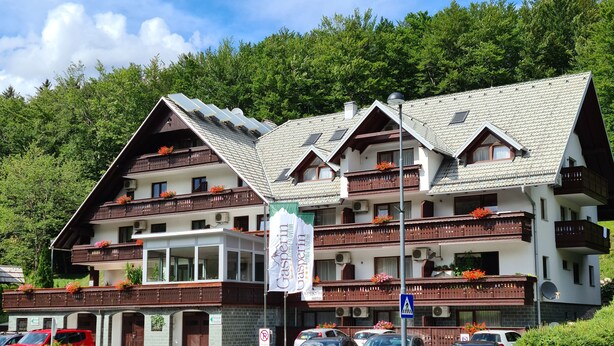 A multi-story hotel with balconies, a ski resort sign, and a parking area.