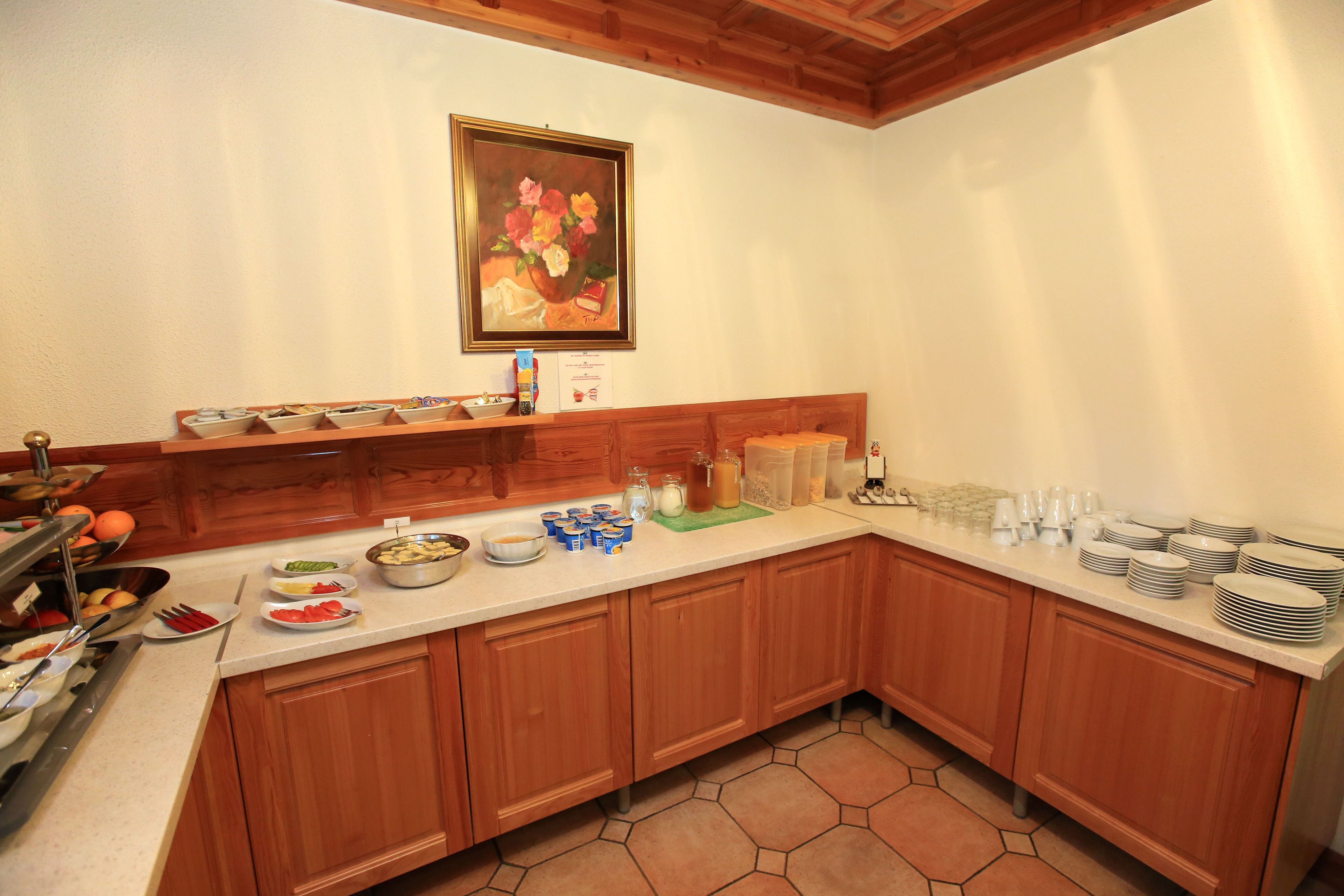 Una cocina con armarios de madera, una encimera blanca y diversos alimentos y utensilios.