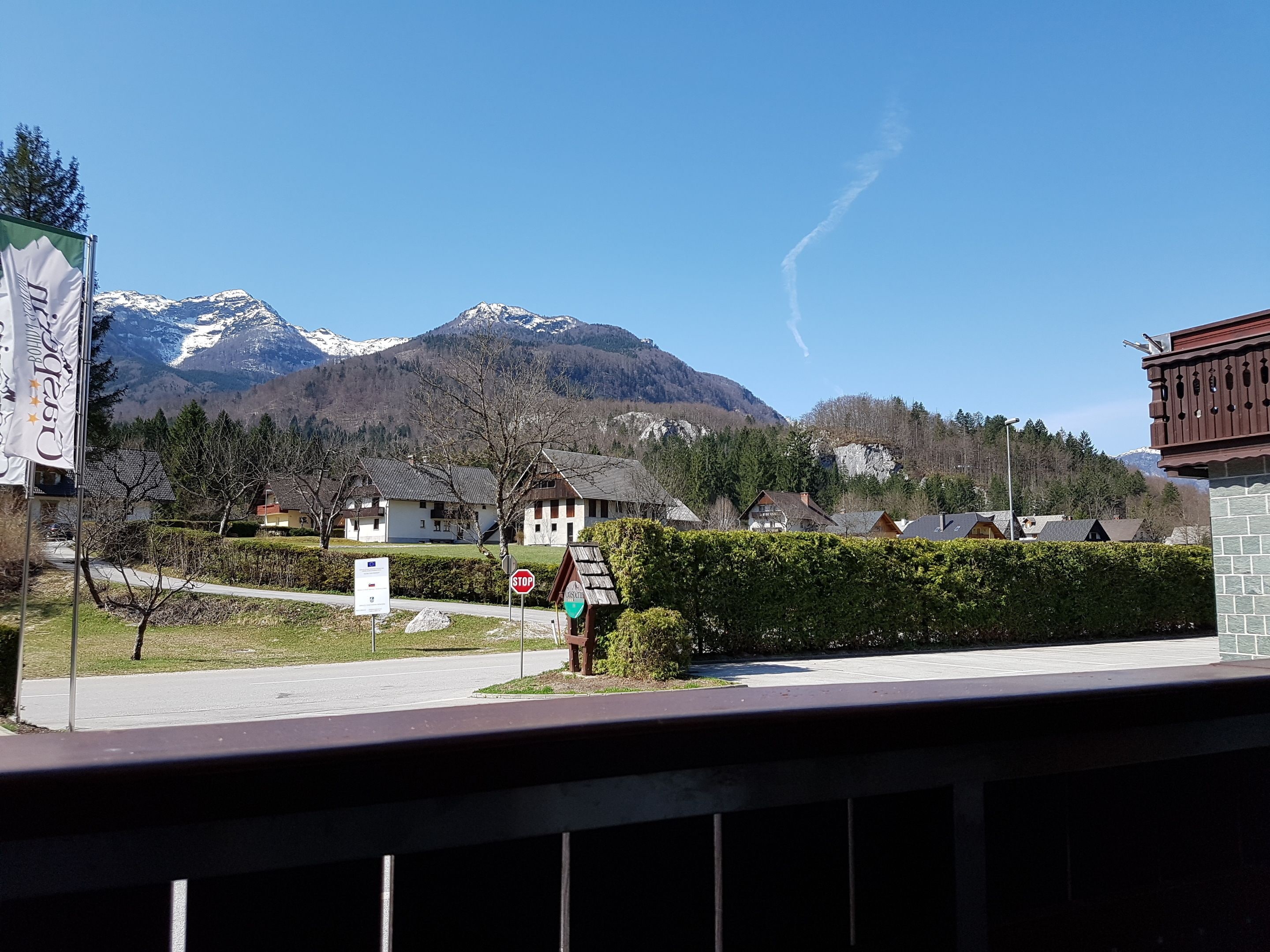 A mountain landscape with snow-capped peaks, a clear sky, and a row of traditional houses with sloped roofs.
