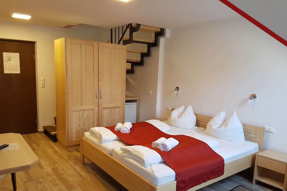 A hotel room with a bed, a desk, a wardrobe, and a staircase.