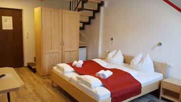 A hotel room with a bed, a desk, a wardrobe, and a staircase.