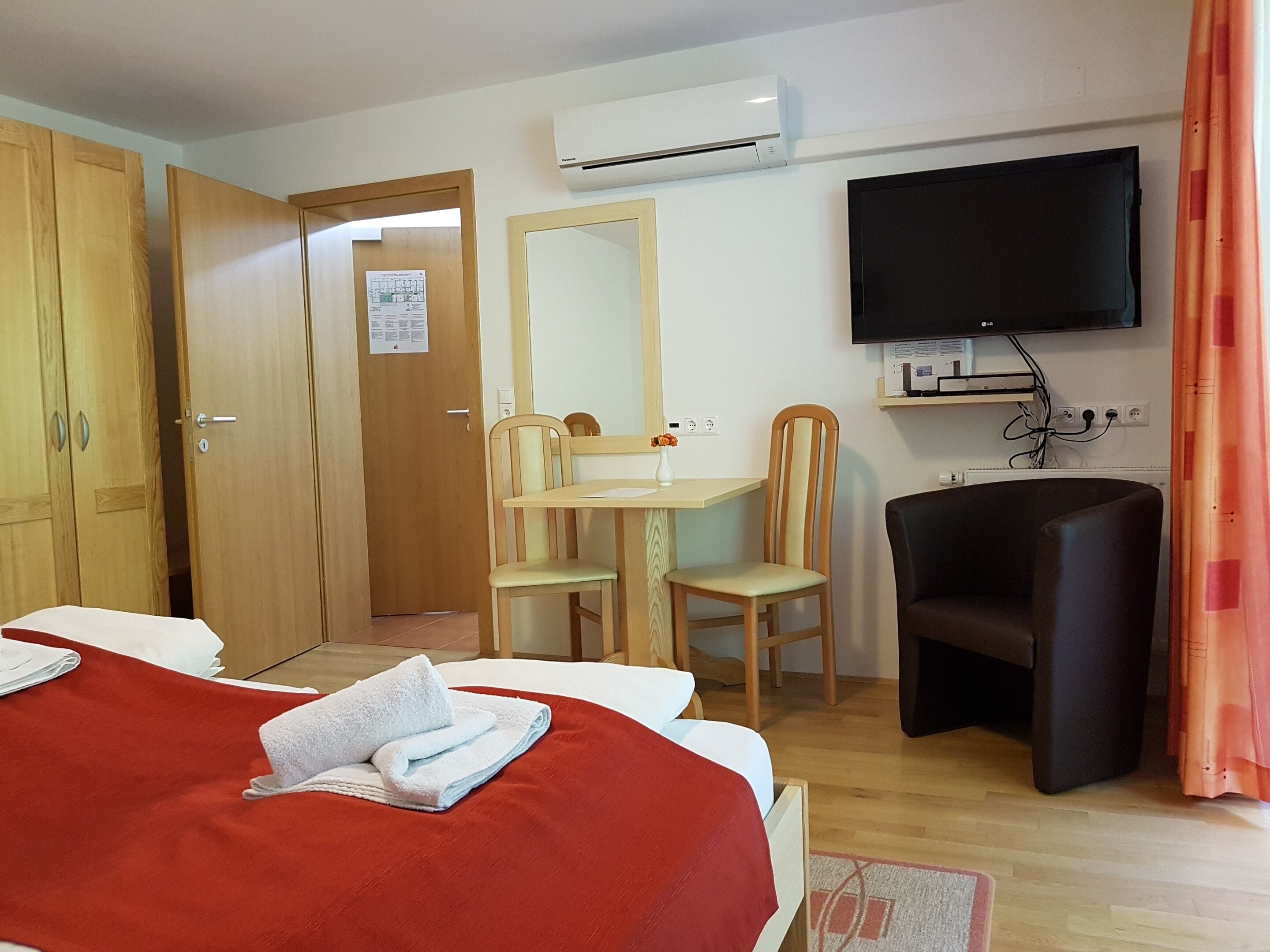 Habitación de hotel con cama, escritorio, silla, televisión y aire acondicionado.