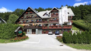 Ein mehrstöckiges Hotel mit Balkonen, einem zentralen Eingang und einem umlaufenden Garten.