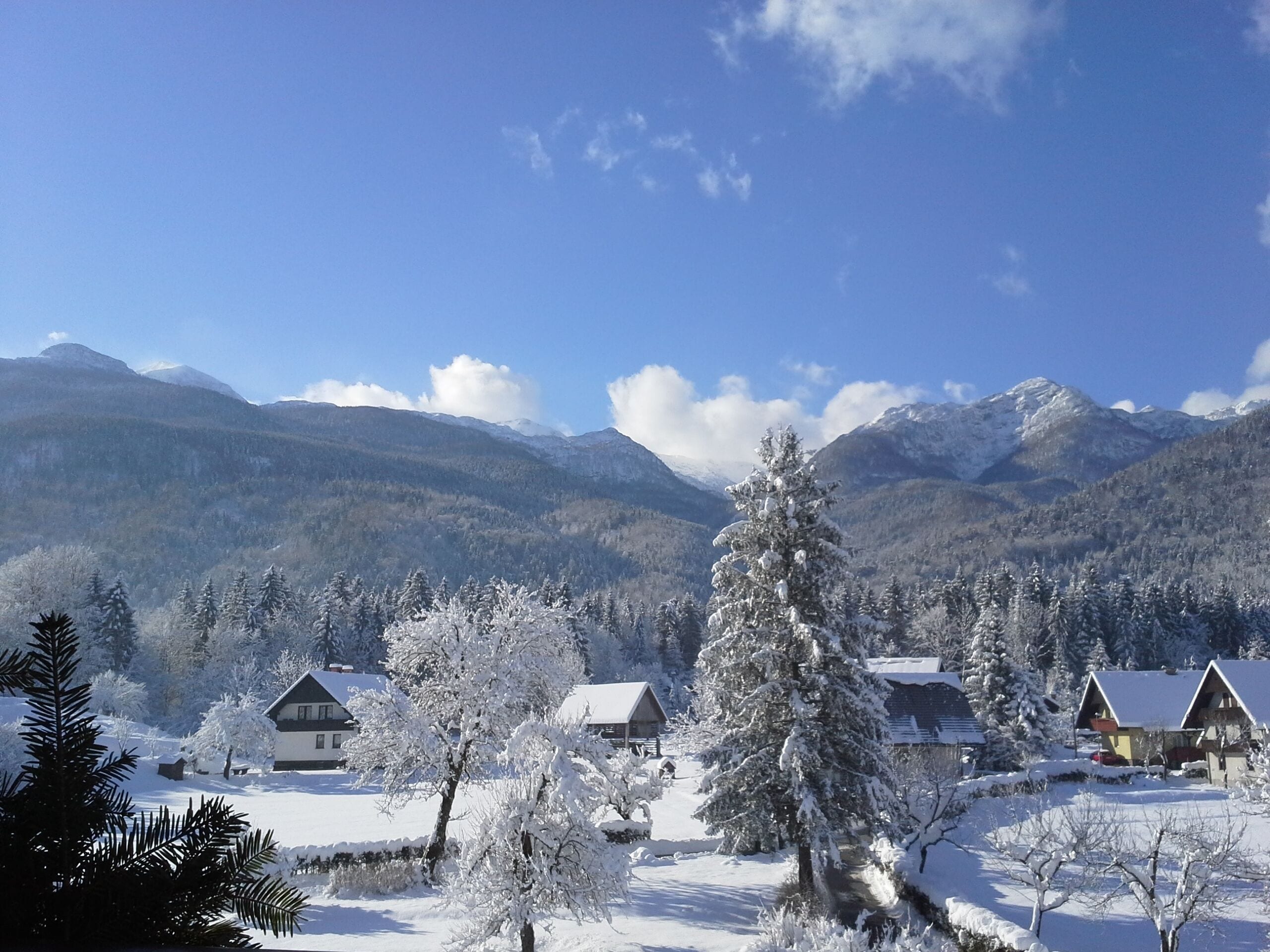 A snow-covered mountain landscape with houses and a clear sky.