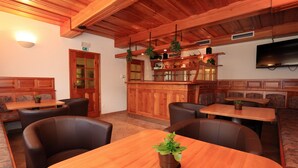 Ein Restaurant mit Holztischen, einer Bar und einem an der Wand befestigten Fernseher.