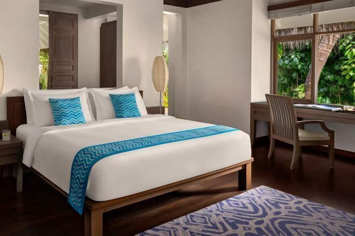 A bedroom with a bed, bedside tables, a desk, and a chair.