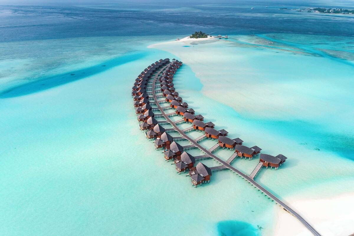 An overwater resort with a continuous row of overwater bungalows connected by a bridge.