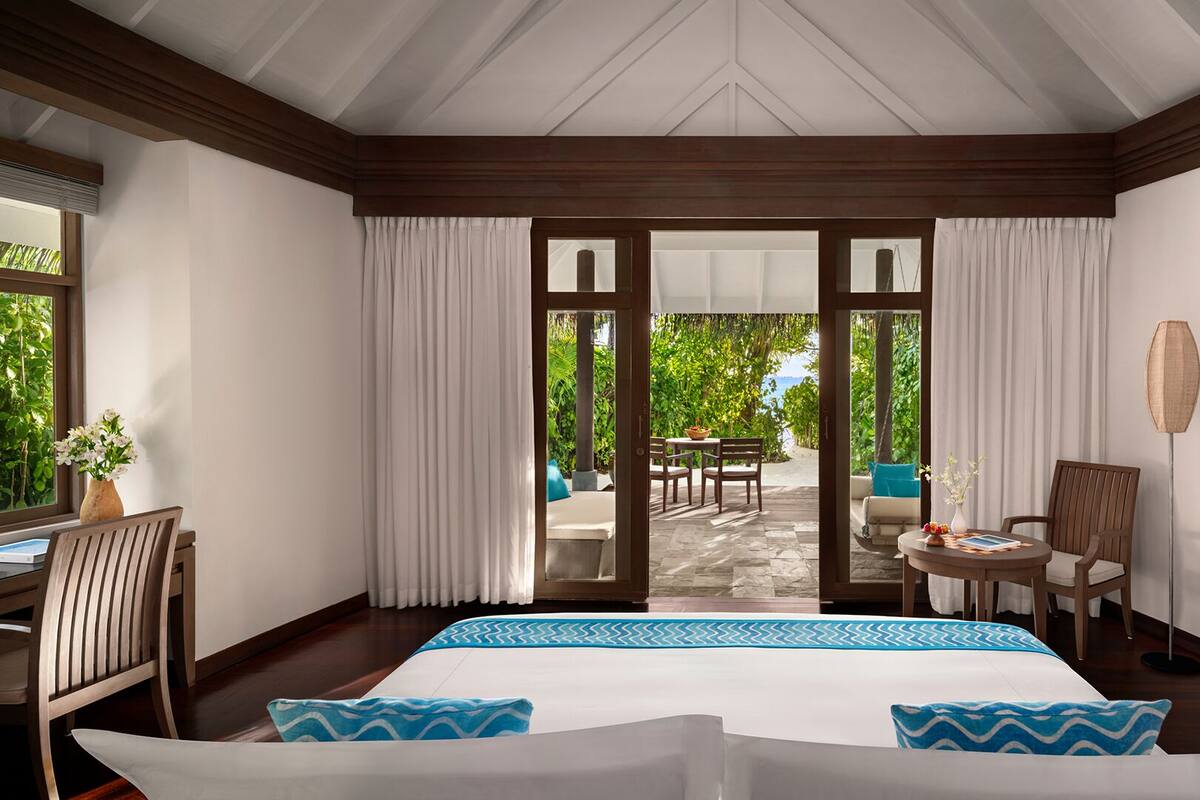 A hotel room with a large bed, a desk, a chair, and a view of the outdoors.