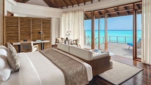 A bedroom with a large bed, a desk, and a view of the ocean.