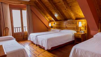 Habitación de hotel con piso de madera, dos camas, una silla y un balcón.