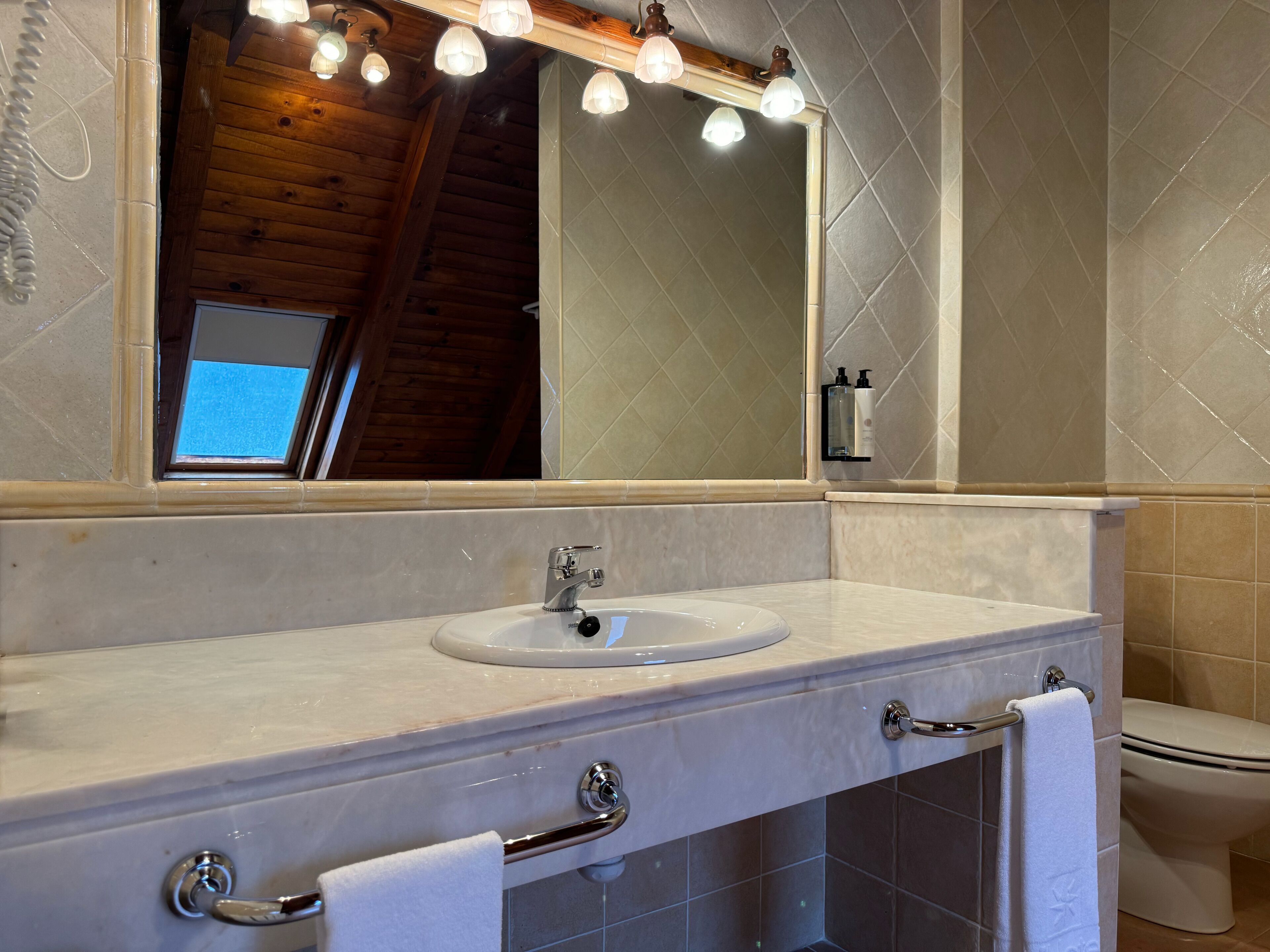 A bathroom with a white sink, a mirror, and a toilet.
