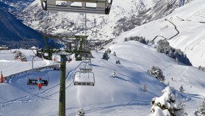 Un telesilla con asiento y una ladera nevada de montaña.