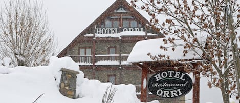 A snow-covered building with a sign reading "HOTEL ORRI Restaurant."