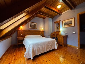 Un dormitorio con techo inclinado, muebles de madera y dos lámparas de noche.