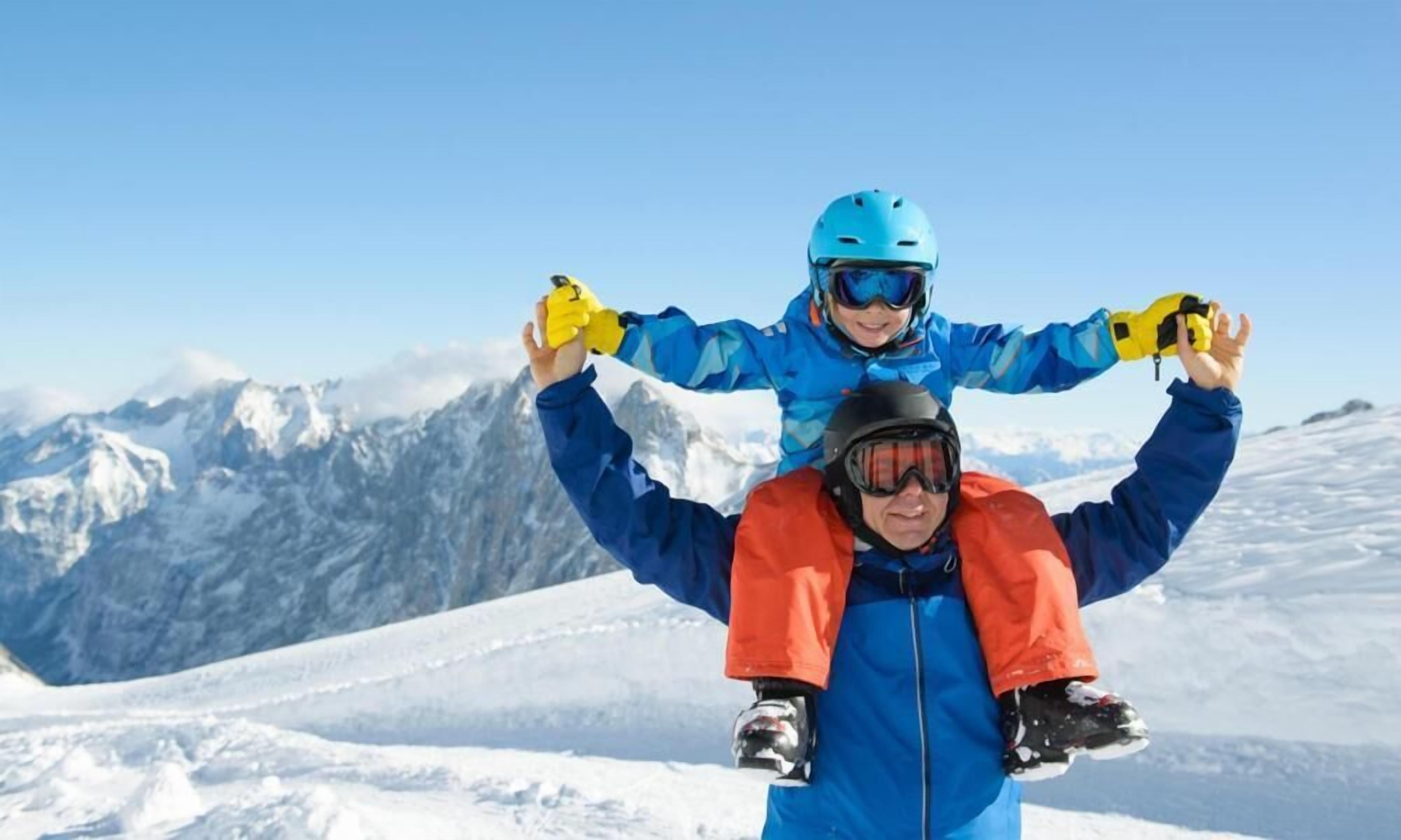 A person carrying another on their shoulders in a snowy mountainous area.